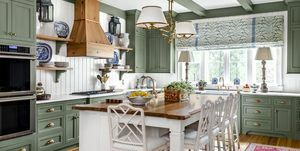 yatıştırıcı yeşil boyalı dolaplar, kirişler ve beyaz panelli duvarlar, tavan ve ada ile eşleştirilmiş döşemeli mutfak