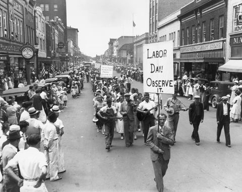 1934'te bir kalabalık kaldırımlardan seyrederken ellerinde tabelalar tutarken sokakta yürüyen insanlarla İşçi Bayramı geçit töreni