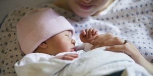 pembe şapkalı yeni doğmuş kız, bir battaniyeye kundaklanmış, annesi çeneden aşağısı hastane önlüğü içinde onu tutarken görülüyor