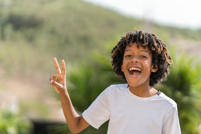 10 yaşındaki Afrikalı Amerikalı çocuk barış işareti yaparken yüksek sesle gülüyor