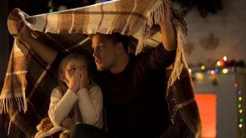 baba elleriyle yüzünü kaplayan ve ekose battaniyenin altında oturan küçük kız için korkunç bir hikaye anlatıyor