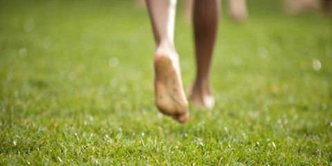 çıplak ayakla çimenlerin üzerinde yürüyen kadın