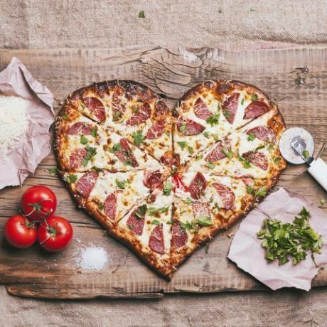 kalp şeklinde pizza ve kesme tahtası üzerinde malzemeler