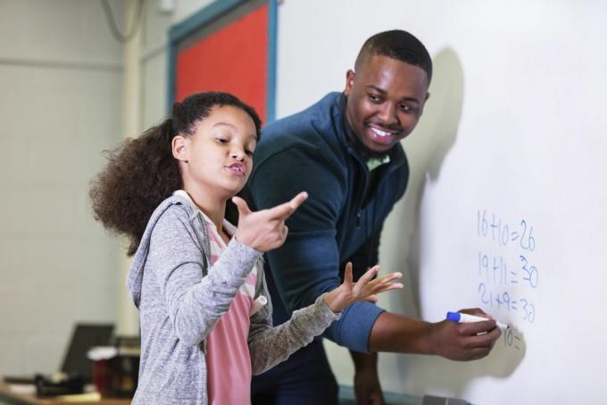 matematik dersinde çok ırklı 9 yaşında bir kız, öğretmeniyle birlikte beyaz tahtanın başında duruyor, genç bir Afrikalı Amerikalı adam 20'li yaşlarındaki öğretmen ilkokul öğrencisine bakıyor, o da odaklanılan sorunun cevabını bulmaya çalışırken bekliyor. kız