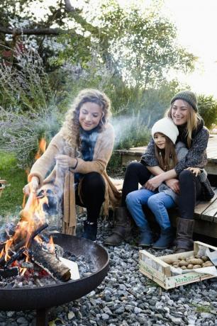 iki kadın ve kız ateş çukurunun yanında oturuyor, rahatlatıcı