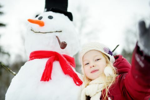 Sevimli küçük kız güzel kış parkta bir kardan adam bina. Bir karda oynayan sevimli çocuk.