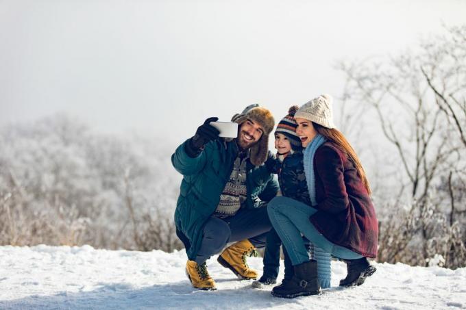 aile kış gününde karlı ormanda selfie çekiyor