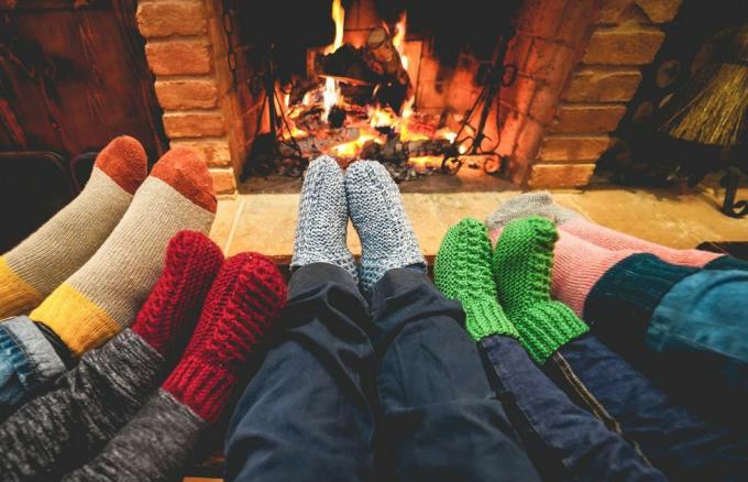 Şöminenin önünde sıcak çoraplar giyen mutlu ailenin bacak görünümü kış, aşk ve rahat konsept orta gri yün çoraplara odaklanıyor